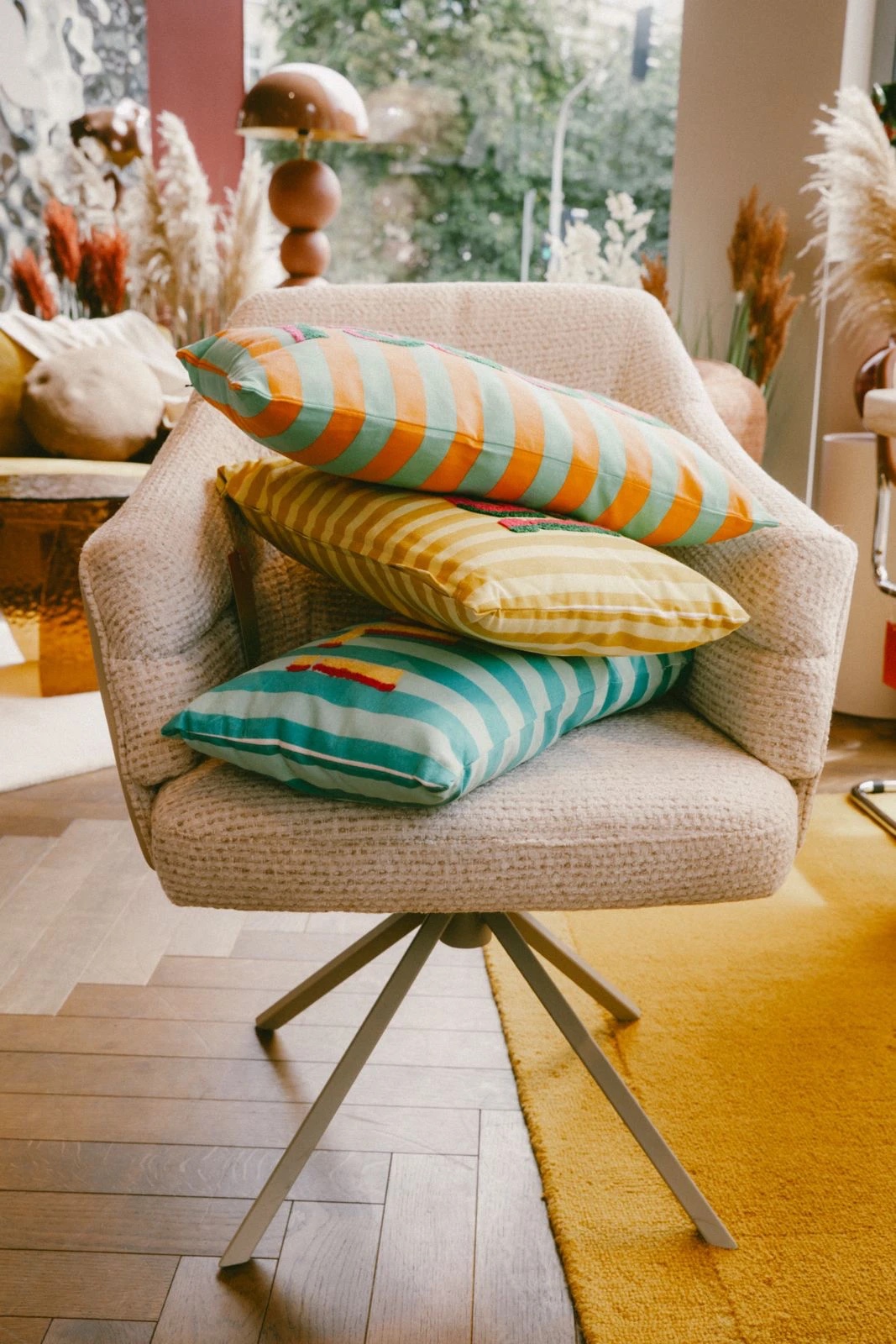 Three striped cushions stacked on a boucle swivel armchair in an Etnika store.