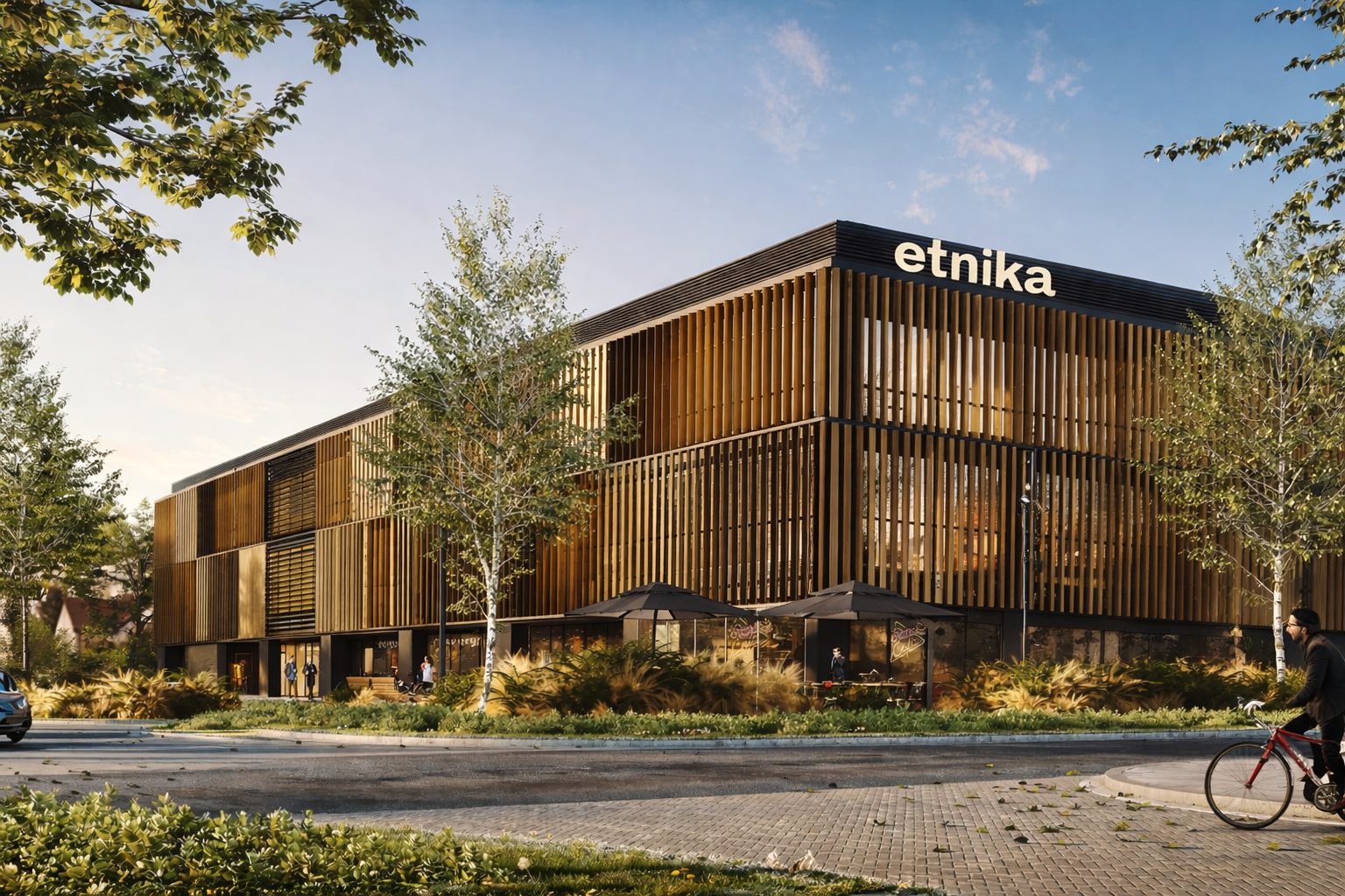 The Etnika flagship store: a long timber-screened building lit from within at dusk, set among birch trees.