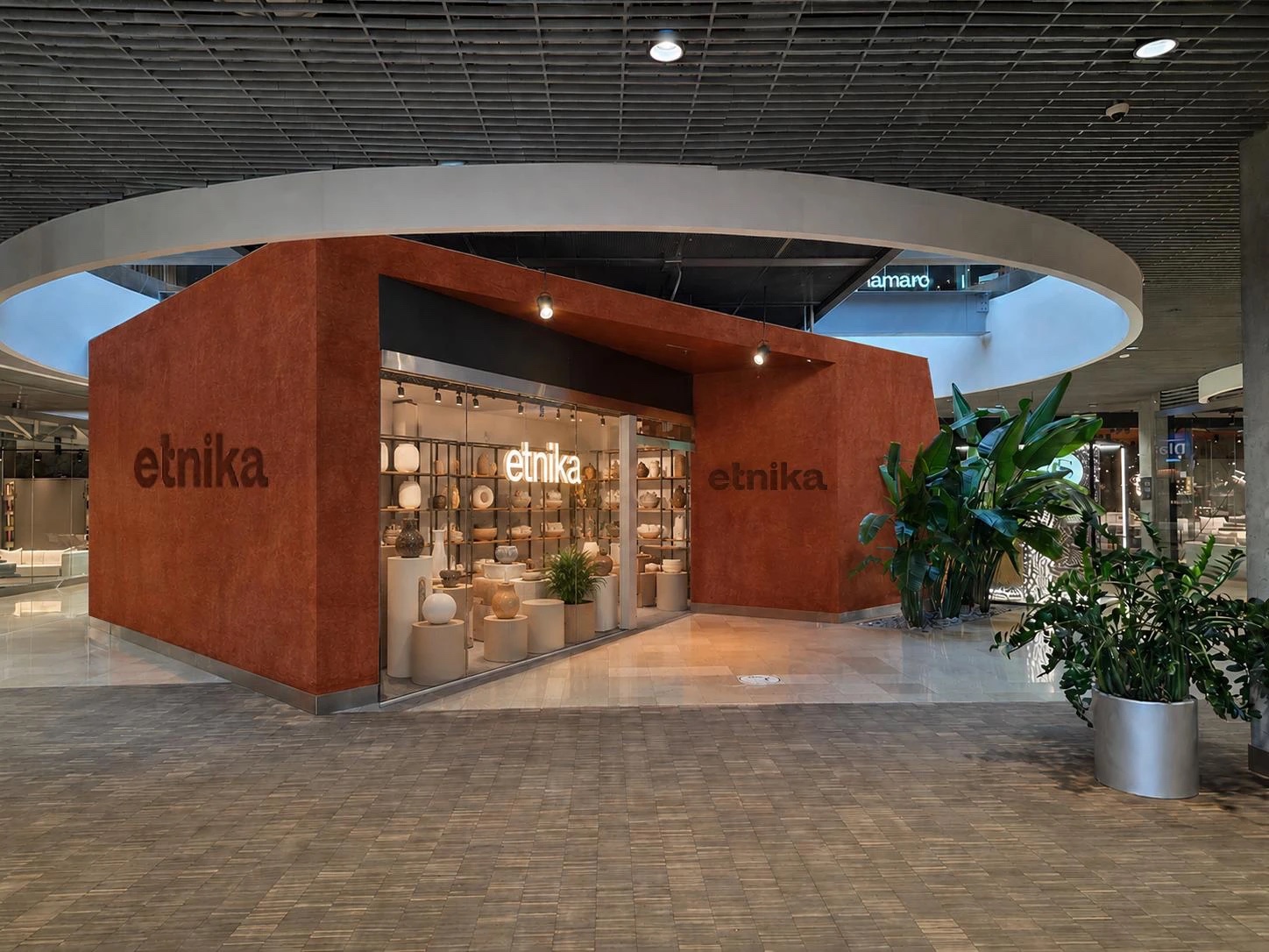 The compact Etnika urban format: a freestanding red unit with a lit display window of ceramics.